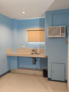 a kitchen with a counter with a sink and a microwave at Glory Hotel Cubao in Manila