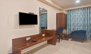 a room with a tv and a table and chairs at Hotel Luxura, Ahmedabad in Ahmedabad