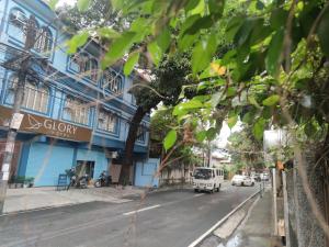 a city street with a blue building and a white van at Glory Hotel Cubao in Manila