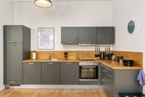 a kitchen with gray cabinets and a wooden floor at MEL&BENS Loft-Appartements Terrasse Weserstadion in Bremen