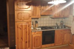 uma cozinha com armários de madeira, um lavatório e um fogão em Appartamento piano terra in centro paese. em Carona