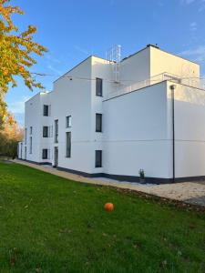 a white building with an orange ball in the grass at Apartamenty HELIOS in Jastrzębia Góra