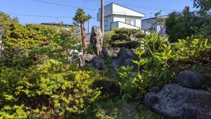 un jardín con rocas y plantas frente a una casa en Showai, en Noboribetsu