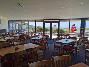 a restaurant with wooden tables and chairs and windows at Snowdonia Sunbeach Holiday Sea and Mountain view in Llwyngwril
