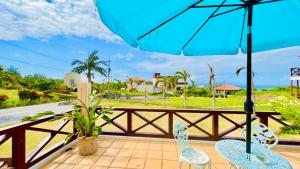 einen Balkon mit 2 Stühlen und einem Sonnenschirm in der Unterkunft Palm Villa Ishigakijima karei in Ishigaki-jima