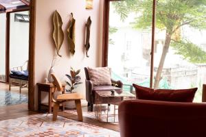 a living room with furniture and a large window at Tints of Blue Hotel in Bangkok