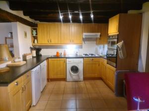 a kitchen with wooden cabinets and a washing machine at la Petite Maison De Vacances in Oradour-Saint-Genest +3 photos