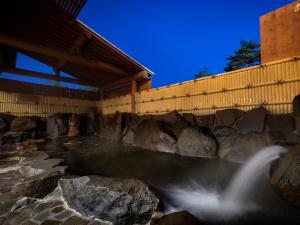a waterfall in a pool of water next to a building at Madarao Kogen Hotel in Iiyama