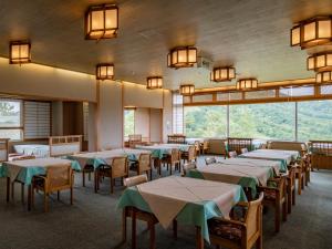 un comedor con mesas, sillas y ventanas en Madarao Kogen Hotel, en Iiyama