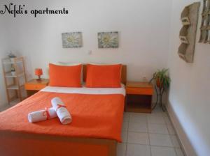 タソスにあるNefeli's Apartmentsのベッドルーム1室(オレンジのシーツとオレンジの枕が備わるベッド1台付)