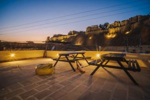 two picnic tables on a roof with a view of a castle at Moustache Jaisalmer in Jaisalmer