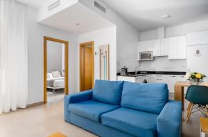 ein blaues Sofa im Wohnzimmer mit Küche in der Unterkunft Suites Del Pintor in Málaga