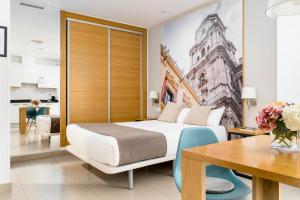 マラガにあるスイーツ デル ピントールのベッドとダイニングルームが備わるホテルルームです。