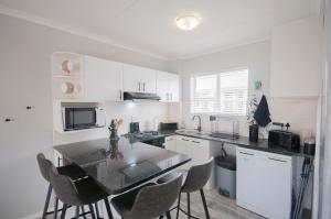 a kitchen with white cabinets and a table and chairs at Big Bay Beach Club 134 in Bloubergstrand