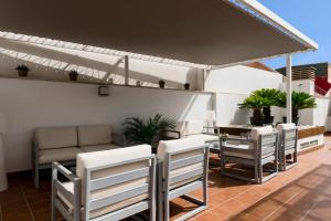 eine Terrasse mit weißen Stühlen und einem Sonnenschirm in der Unterkunft Suites Del Pintor in Málaga