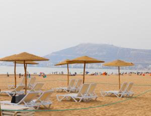 un gruppo di sedie e ombrelloni in spiaggia di Hotel Argana Agadir ad Agadir