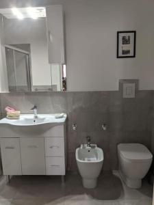 y baño con lavabo, aseo y espejo. en Casa di Clara in Piazza, ideale per smartworking, en Amandola