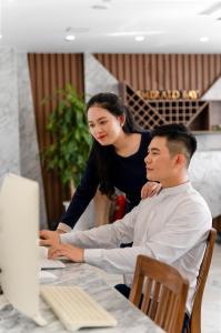 un homme et une femme assis à une table utilisant un ordinateur dans l'établissement Emerald Bay Hotel & Spa, à Nha Trang