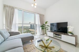 a living room with a couch and a tv and a table at Immaculate 1BR apartment at Carson C in Dubai