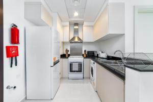 a kitchen with white cabinets and a sink at Immaculate 1BR apartment at Carson C in Dubai