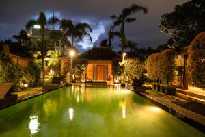 a swimming pool with green water at night at Villa Berawa in Canggu