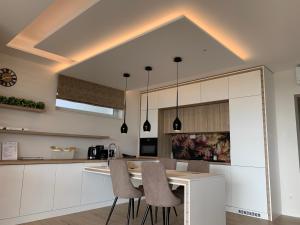a kitchen with white cabinets and a table with chairs at SXRD Luxus Apartmanok in Szekszárd