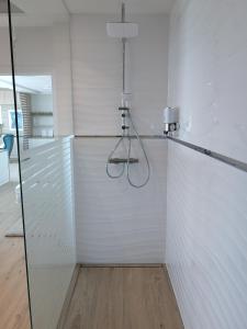 a glass shower stall in a white room at SXRD Luxus Apartmanok in Szekszárd