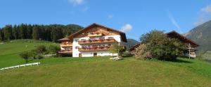 a large building on top of a green hill at Ferienwohnung Maiernhof Bauernhof Ultental in San Pancrazio dʼUltimo