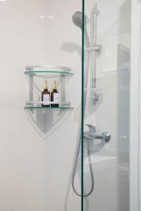 Un estante de cristal en una ducha con dos botellas. en Urbanite Hotel, en Vientiane