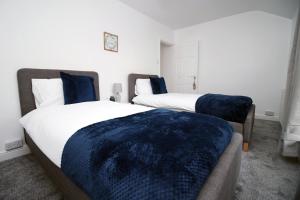 um quarto com 2 camas e almofadas azuis em Wern farm cottage em Pontypool