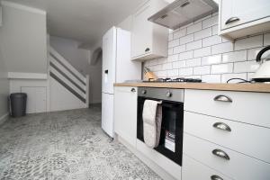 uma cozinha com armários brancos e um fogão em Wern farm cottage em Pontypool