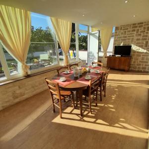 a dining room with a table and chairs and windows at Casa Letizia in Umag