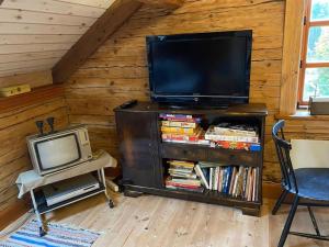 a living room with a tv and a tv stand with a tv at Södragården - traditionally Swedish in Annerstad