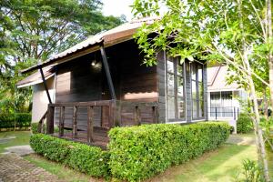 een houten hut met een veranda en wat struiken bij Chanpraya Resort in Chanthaburi