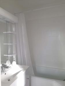 a white bathroom with a sink and a mirror at Studio proche du centre ville et de la plage in Villers-sur-Mer