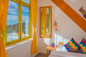 a bedroom with yellow curtains and a bed and windows at goSTOPS Bir, Landing Site in Bīr