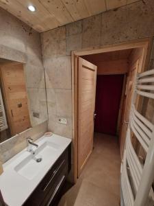 baño con lavabo, espejo y puerta en Charmant T2 rénové- Praloup 1600-parking privé, proche station en Uvernet-Fours