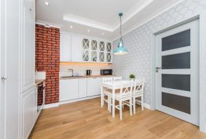a kitchen with a white table and a brick wall at Cztery Oceany 209 in Gdańsk