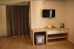 a room with a desk and a tv on the wall at Regent Ngamwongwan Hotel in Nonthaburi