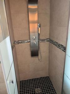 a bathroom with a shower with a black tile floor at Maison Rénovée Aux Portes Du Circuit Des 24h in Mulsanne