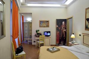 フィレンツェにあるホテル ヴァザーリのベッド、デスク、テレビが備わる客室です。