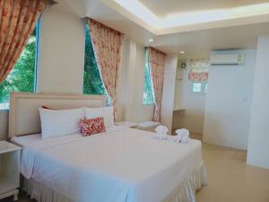 1 dormitorio con 1 cama blanca grande y ventanas en Banlomnow, en Chiang Rai