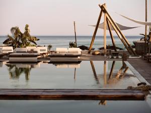 a pool with white lounge chairs and the ocean at GARDELLI RESORT in Laganas