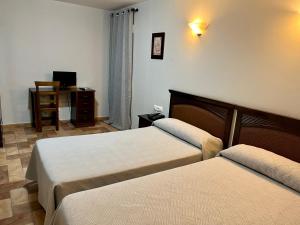 a hotel room with two beds and a television at Hotel Cervantes in Zafra