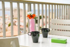 馬賽的住宿－Vallon des Auffes - Vue imprenable sur la mer，两个咖啡杯和一个花瓶,桌子上放着花