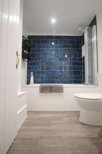 a bathroom with a toilet and a blue tile wall at Dexter's House in Kent