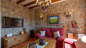 a living room with a red couch and a tv at El Molar Ronda by Ruralidays in Ronda
