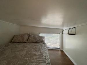 a small bedroom with a bed and a window at Tiny House in the Bush - a minute from town centre in Raetihi