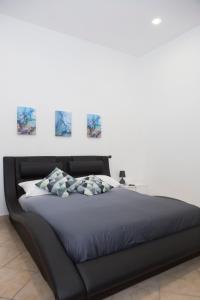 um quarto com uma cama preta com três pinturas na parede em Airport House em Nápoles