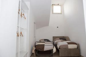 Duas camas num quarto branco com uma janela em Airport House em Nápoles